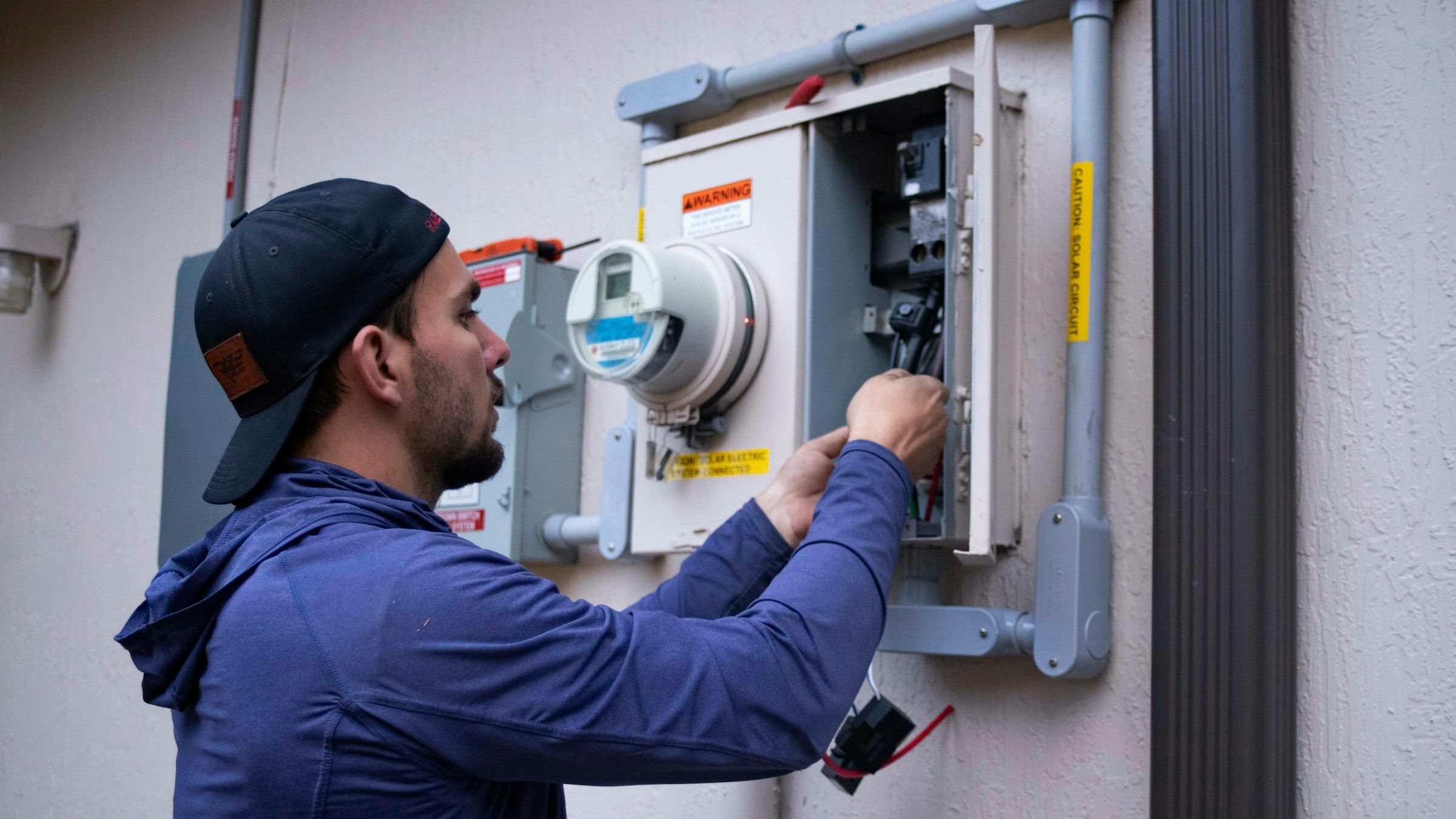 Electrician working on an electric meter outside a house