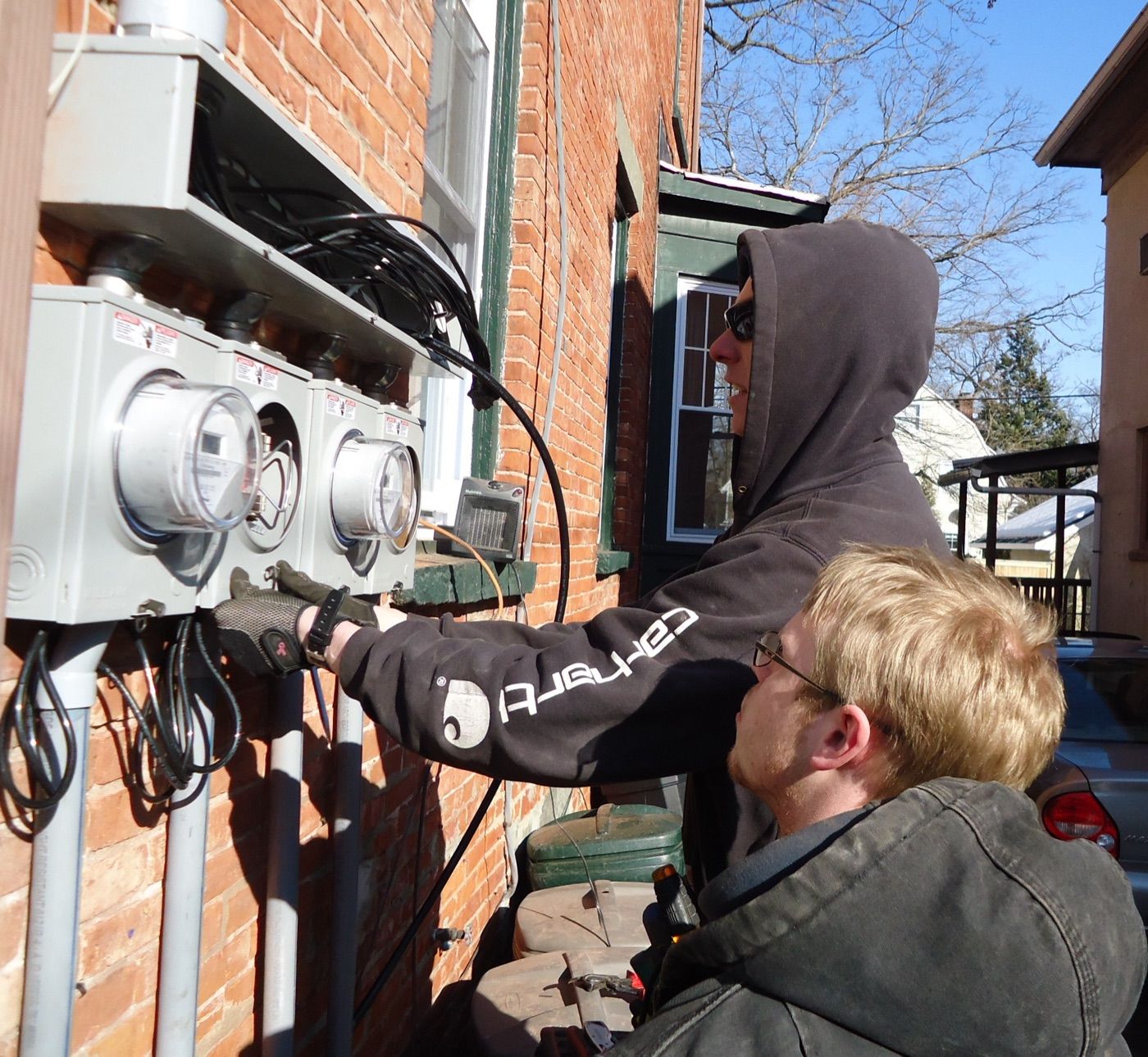 Two electricians wiring meter panels on a house in New Jersey